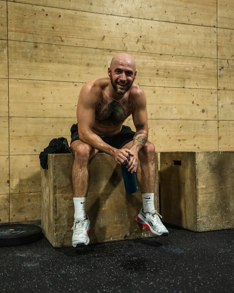 Atleta sonriente sentado en un cajón de madera tras entrenar