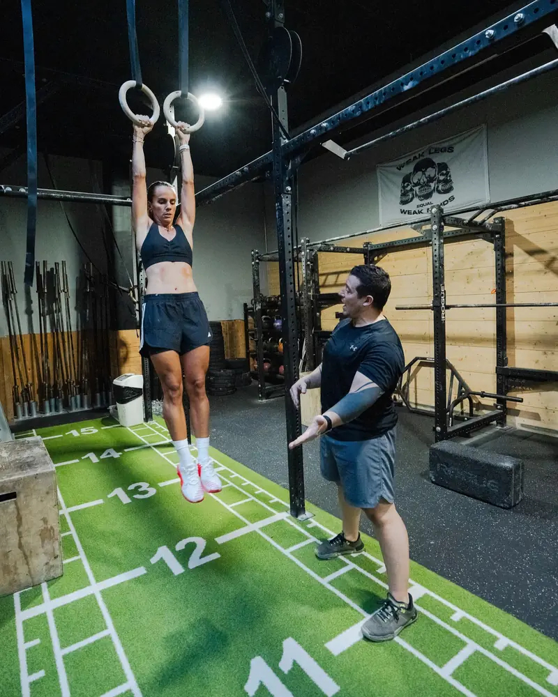 Un coach guía a una atleta colgada de las anillas